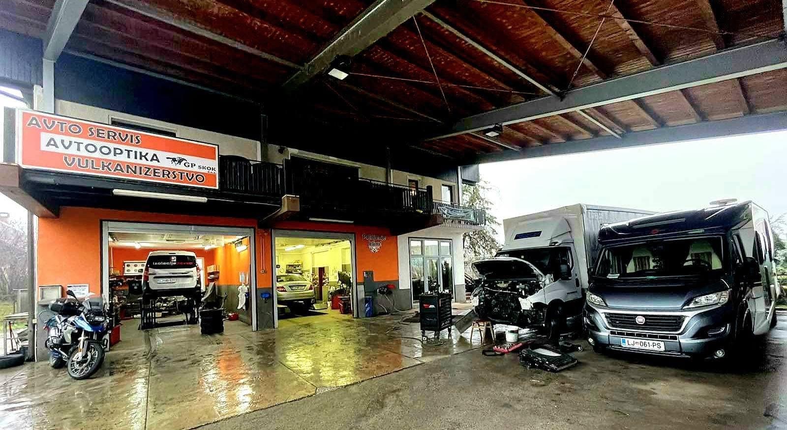 Dvorišče Avtoservisa GP Skok v Mengšu s tablo in dvema camperjema v servisu